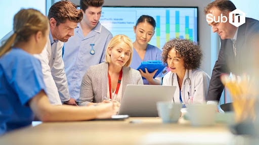 Medical team meeting around laptop, discussing hiring IT staff