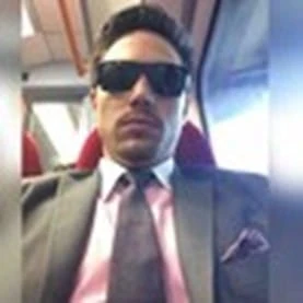 Man in suit and sunglasses on a train