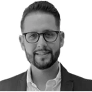 Man wearing glasses and a suit smiling